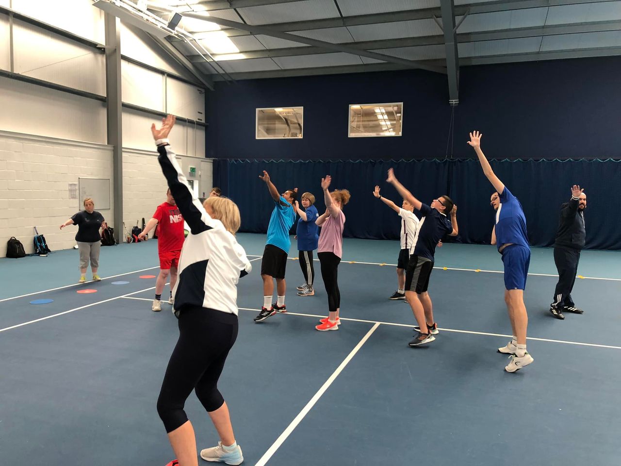 Sue and the players in the Nike Tick position (left arm pointing to the sky, and right arm bent touching the back of the head) - working on the overarm serve.