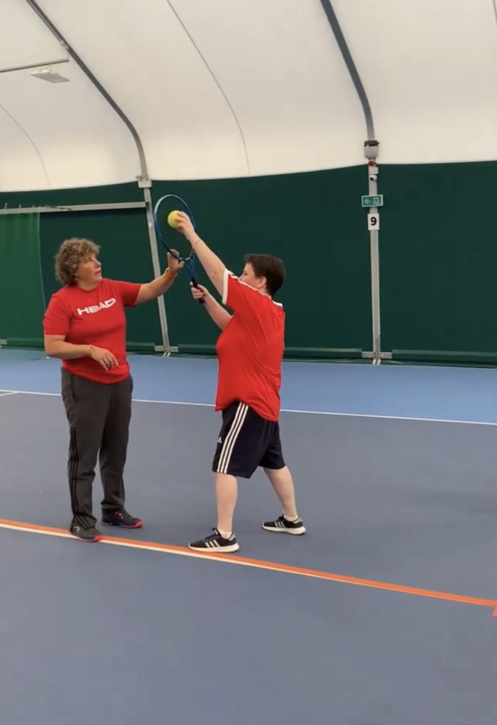 Lou showing a B1 player how to hit a slice serve