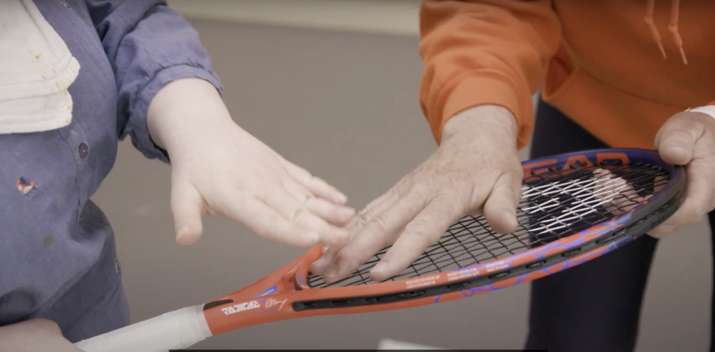 Player and coach touching the strings of a tennis racket