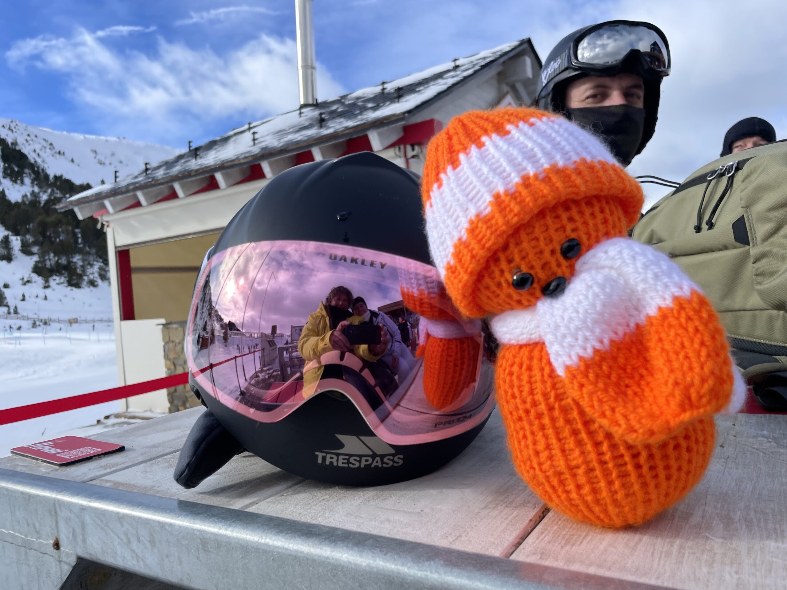 Tango leaning against a Ski helmet and goggle, with image of Loui in the goggles