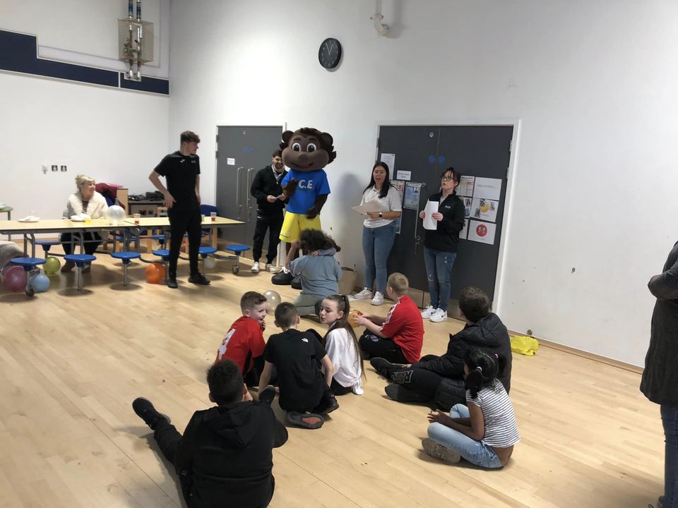 Children sat on the floor indoors waiting to play party games