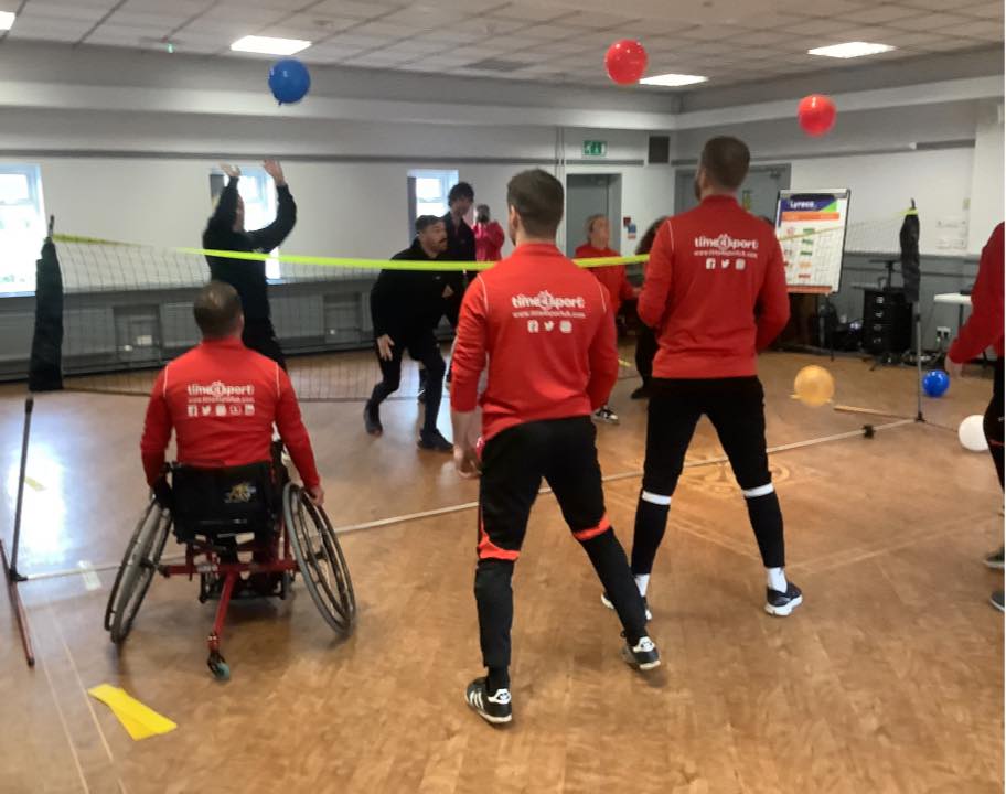 Coaches playing ballon volleyball, one playing using a wheelchair